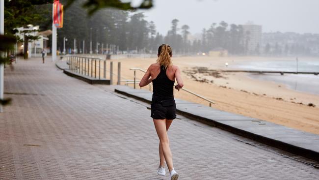 A lone jogger is seen exercising on Manly beachfront today. Picture: Lee Hulsman/Getty