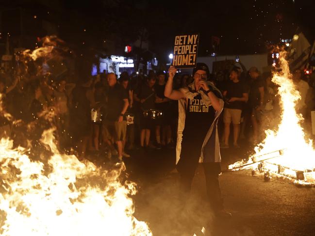 A protester holds a sign beside a bonfire on second day of demonstrations demanding a Gaza deal in Tel Aviv, Israel. Picture: Getty Images