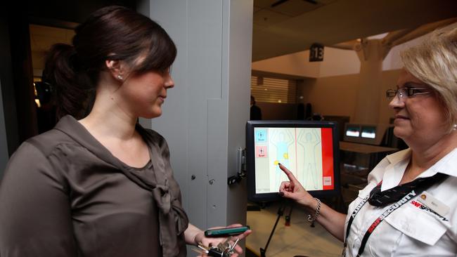 A Sydney security staff member shows to the media how the body scanners at Sydney Airport operate back in 2011.