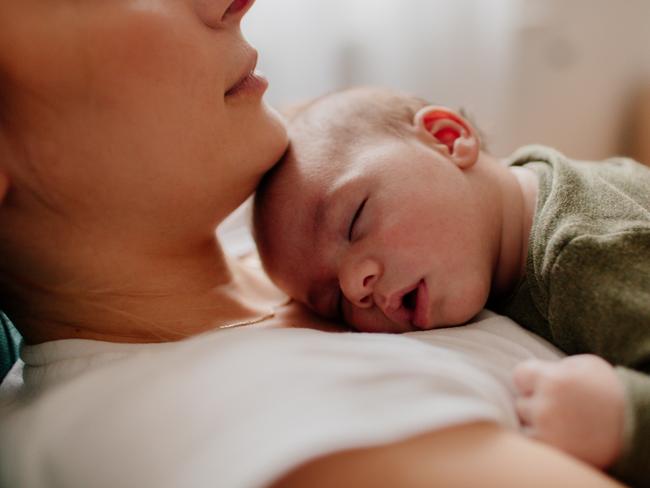 Photo of a young mother holding her newborn baby, while putting him to sleep