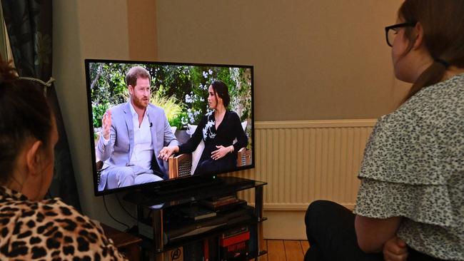 A family gather around the television in Liverpool, north west England to watch Prince Harry and his wife Meghan's explosive tell-all interview on CBS with Oprah Winfrey. (Photo by Paul ELLIS / AFP)