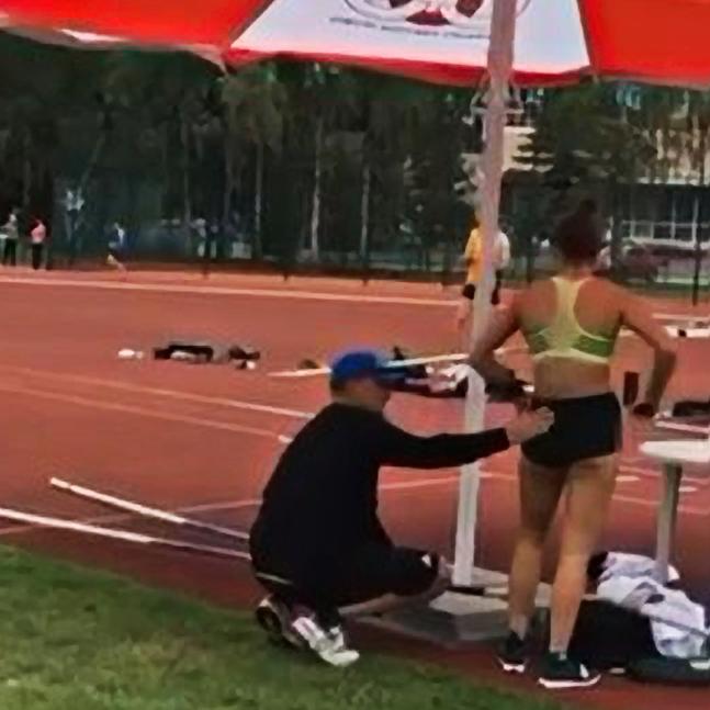 Still from an video posted to Instagram showing coach Alex Parnov stroking the back and backside of Olympic pole vaulter Nina Kennedy.