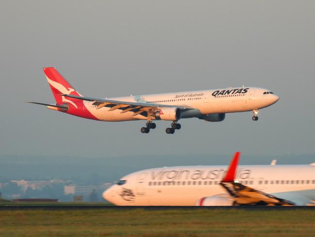 A Qantas Airbus A330-303 plane, registration VH-QPB, coming into land from the south on the main runway of Sydney Kingsford-Smith Airport as flight QF128 from Hong Kong. In the foreground is a Virgin Australia Boeing B737-8FE plane, registration VH-YFZ, taxiing before departure as flight VA1528 to Hobart.  This image was taken from Mill Stream Lookout, Botany Bay on a sunny morning at sunrise on 30 March 2024.27 October 2024Kendall HillPhoto - iStock