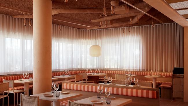 The dining area features striped banquettes and rattan furniture.