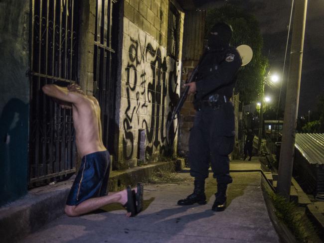 Police officers search a gang suspect in the San Salvador community controlled by the Mara Salvatrucha in the world’s murder capital. Picture: News Corp.