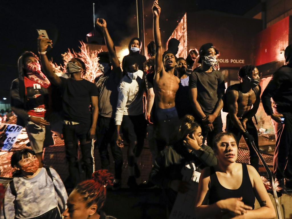 Protesters demonstrate outside of a burning police building over the death of George Floyd, a black man who died in police custody. Picture: AP Photo/John Minchillo.