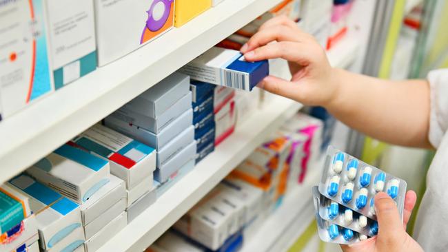 Pharmacist holding medicine box and capsule pack in pharmacy drugstore. Picture: iStock