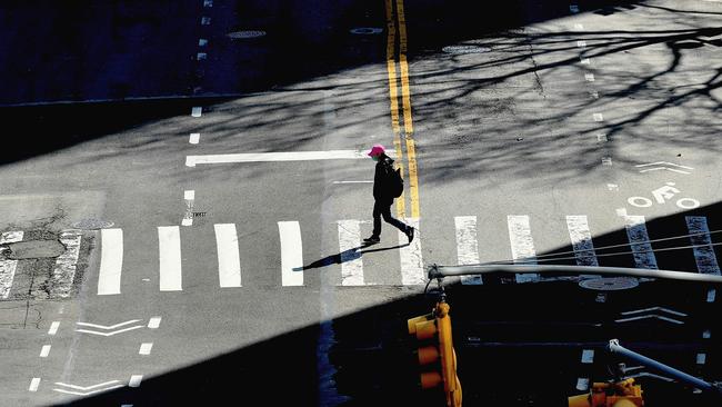 A person crosses an empty street in New York, where half of all the US infections have occurred.