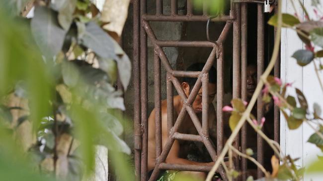 Thai and Burmese fishing boat workers sit behind bars inside a cell at the compound of a fishing company in Benjina, Indonesia.