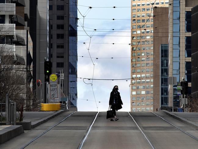 A woman crosses a deserted Collins St in Melbourne’s CBD during the stage-four lockdown. Picture: David Geraghty