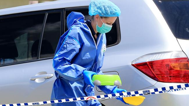 A police scenes of crimes officer brings animal food bowls out of the residence. Pic Tim Marsden