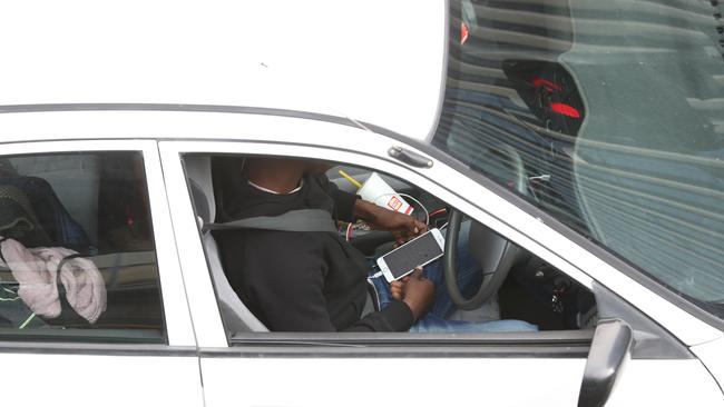 A driver holds his phone on the corner of Montefiore Rd and North Tce on Friday. Picture: Tait Schmaal