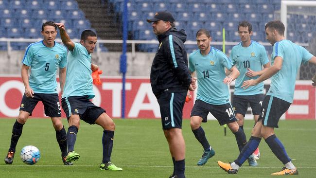 Australia's head football coach Ange Postecoglou (C) looks at his players.