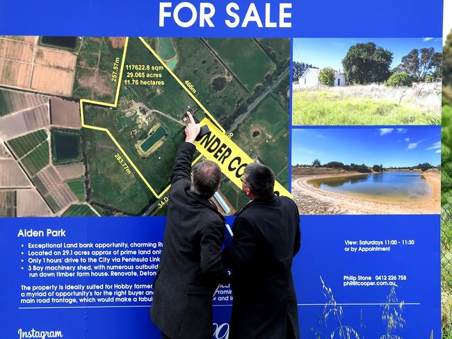 Detectives examine a map of the property on a For Sale sign. Picture: Nicole Garmston