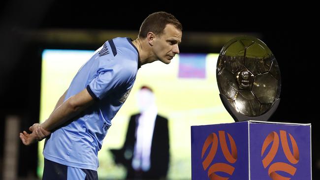 Alex Wilkinson of Sydney FC looks at the Premiers Plate presented to his team at Leichhardt Oval.