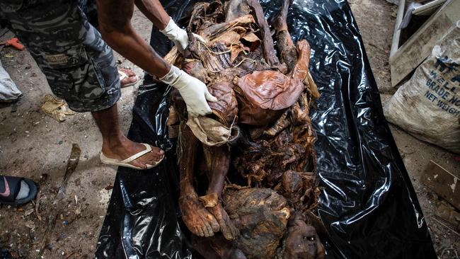 A worker arranging cadavers in various stages of decomposition at the morgue of Henry's Funeral Homes in Manila. Picture: AFP/ Noel Celis.