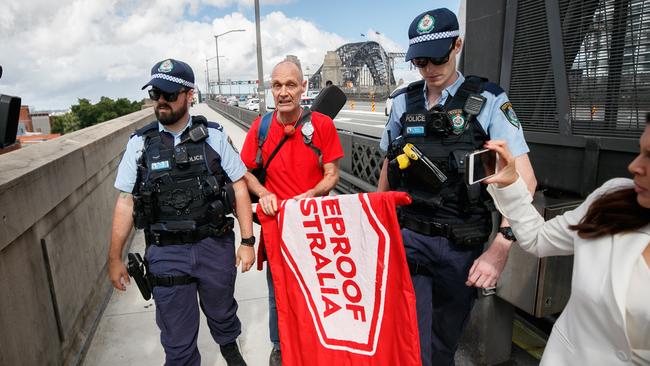 A Fireproof Australia protester is escorted off the Harbour Bridge. Photo: Tim Pascoe