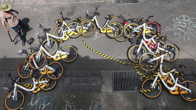 A ‘bike wrangler'’ hired by oBike dismantles an art installationthat was stuck to a brick wall in a lane way in Fitzroy in 2017. Picture: Getty Images