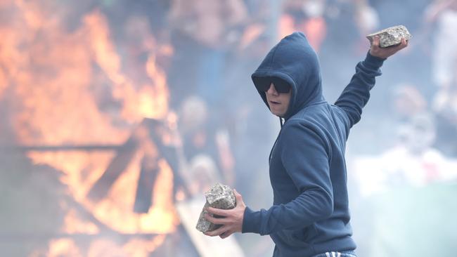 ROTHERHAM, ENGLAND - AUGUST 4: An anti-migration protester prepares to throw a piece of concrete during riots outside of the Holiday Inn Express in Manvers, which is being used as an asylum hotel, on August 4, 2024 in Rotherham, United Kingdom. Yesterday saw widespread violence as Far-right agitators in Liverpool and Manchester rioted and looted shops. Police were attacked and injured and dozens of arrests were made. (Photo by Christopher Furlong/Getty Images)