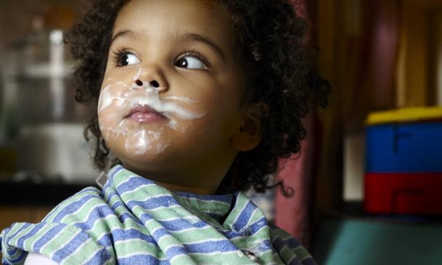 Child eating yoghurt on face