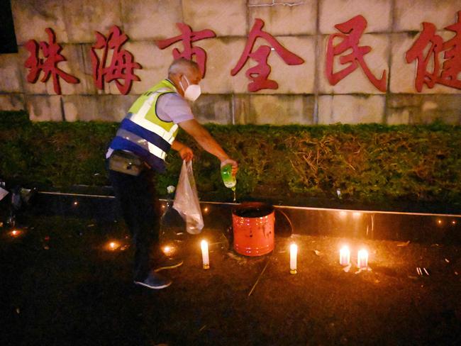 TOPSHOT - A worker douses candles left outside the Zhuhai Sports Centre, a day after a car rammed through the site killing dozens in Zhuhai, in south China's Guangdong province on November 12, 2024. A man killed 35 people and injured 43 more when he ploughed his car into those exercising around a sports centre in the southern Chinese city of Zhuhai on Monday, local police said on November 12, 2024. (Photo by MICHAEL ZHANG / AFP)