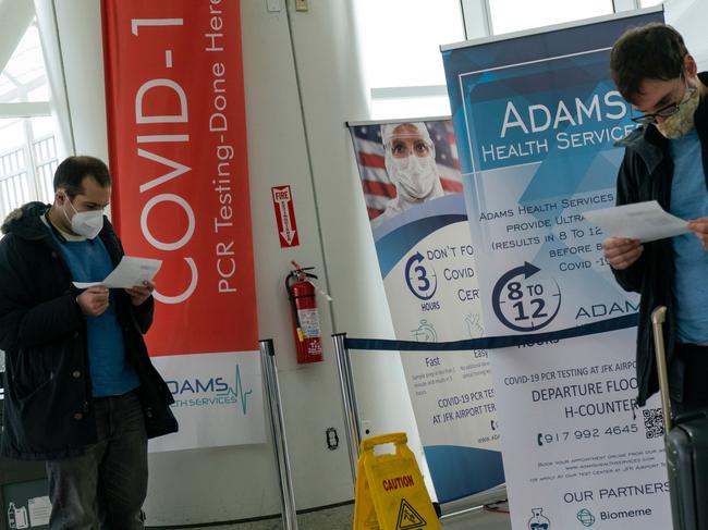 Travellers look at Covid-19 results after being tested inside JFK International airport in New York.