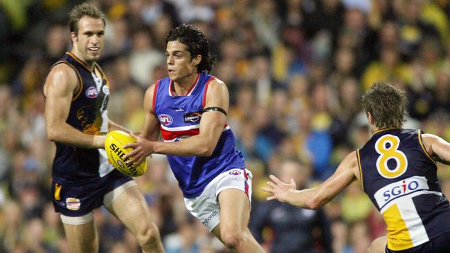 Jordan McMahon steps through Chris Judd and Beau Waters while playing at the Dogs.