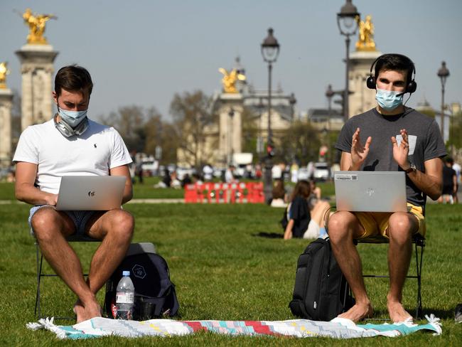 Two men take advantage of the sunshine as they work in front of Paris’ Hotel des Invalides. Picture: AFP