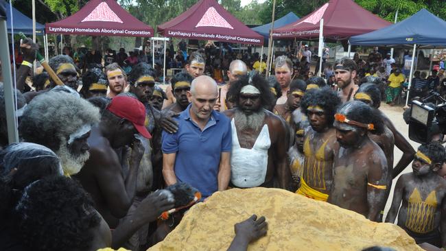 Paul Kelly and Witiyana Marika, surrounded by painted warriors, unveil a plaque dedicated to Mandawuy in his sacred homeland of Biranybirany, June 2018. Picture: Matt Garrick