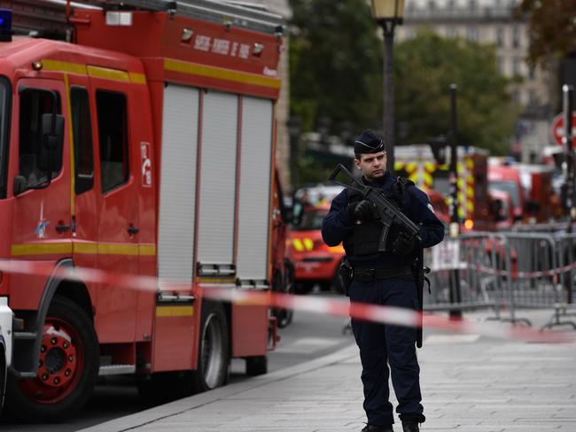 A policeman stands next to firefighter vehicles near police headquarters in Paris. Picture: AFP