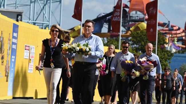 Craig Davidson, CEO of amusement theme park Dreamworld, leads his staff as they prepare to lay flowers outside the park the day after the disaster. Picture: AAP Image/Dan Peled