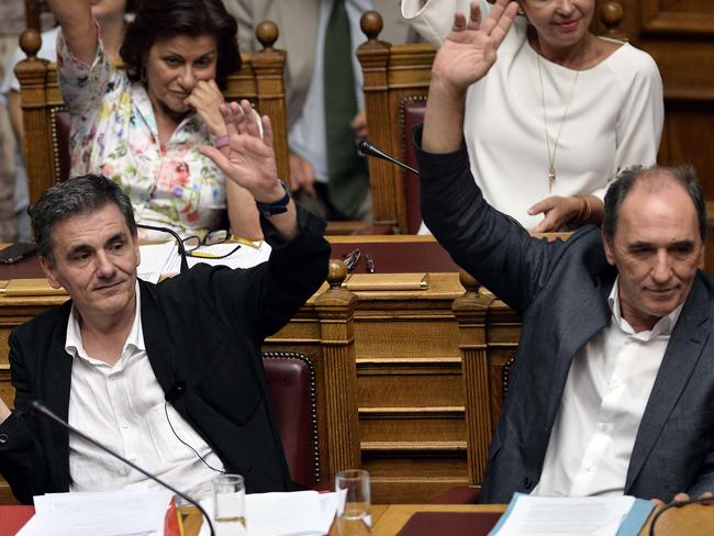 Greek Finance Minister Euclid Tsakalotos (L) and Economy Minister Giorgos Stathakis vote on procedure during a parliamentary debate in Athens early on August 14, 2015. Greek lawmakers held an emergency parliamentary session for a crucial vote on ratifying a hurriedly-concluded bailout deal, but Germany -- Europe's de facto paymaster -- has cast doubt on the agreement. AFP PHOTO / LOUISA GOULIAMAKI