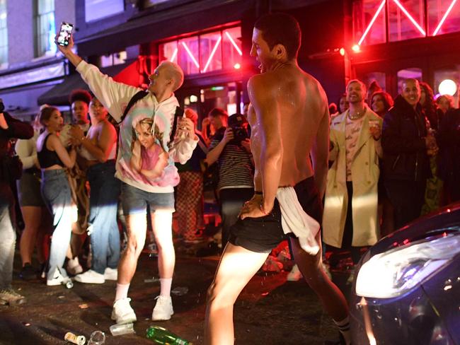 TOPSHOT - A car tries to drive along a street filled with revellers drinking in the Soho area of London on July 4, 2020, after the police re-opened the road at 2300 as restrictions are further eased during the novel coronavirus COVID-19 pandemic. - Pubs in England reopen on Saturday for the first time since late March, bringing cheer to drinkers and the industry but fears of public disorder and fresh coronavirus cases. (Photo by JUSTIN TALLIS / AFP)