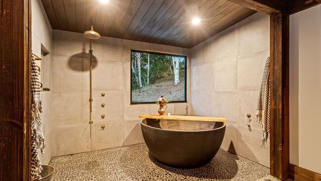 A close-up of the ensuite, which features twin basins, a rain shower and a circular freestanding bath.