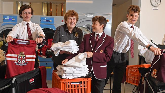 Pauline Coupe, who has been working at Prince Alfred College boarding house for 33 years, with boarders Ned Davies, Year 8, Angus Hodges, Year 7, and Charlie Siemer, Year 7, in the boarding house laundry. Picture: Tom Huntley