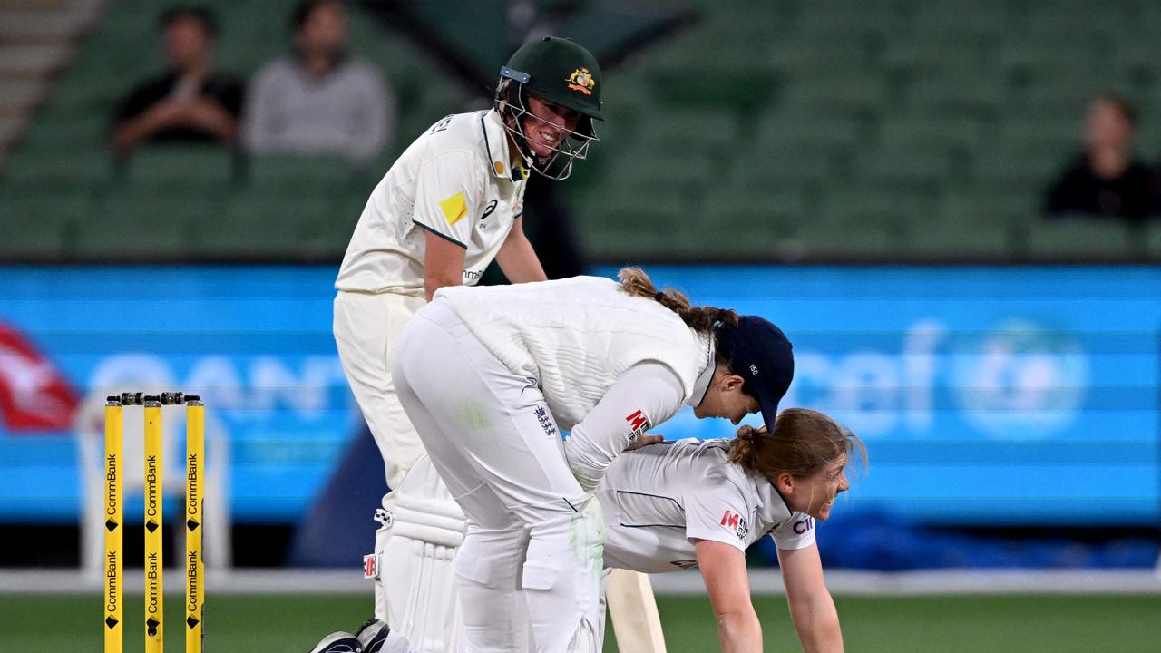 England's Heather Knight reacts in pain as teammate Tammy Beaumont (C) and Australia's Beth Mooney (L) look on during the second day of the women's Ashes cricket Test match between Australia and England at the Melbourne Cricket Ground (MCG) in Melbourne on January 31, 2025. (Photo by William WEST / AFP) / --IMAGE RESTRICTED TO EDITORIAL USE - STRICTLY NO COMMERCIAL USE--