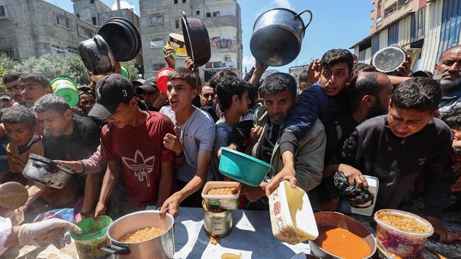 Palestinians queue for a portion of hot food distributed by a charity kitchen at the Nuseirat refugee camp in the central Gaza Strip. Picture: AFP.