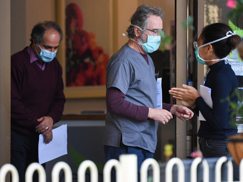 People wearing face masks are seen at the entrance of the Menarock Life aged care facility, where a cluster of some 28 new infections had been reported, in the Melbourne suburb of Essendon on July 14, 2020, as the city battles fresh outbreaks of the COVID-19 coronavirus. - Authorities on July 13 reported 177 new infections in and around Melbourne after the Australian city imposed a six-week lockdown on July 9, with surrounding Victoria state sealed off from the rest of the country in an effort to contain the virus. (Photo by William WEST / AFP)