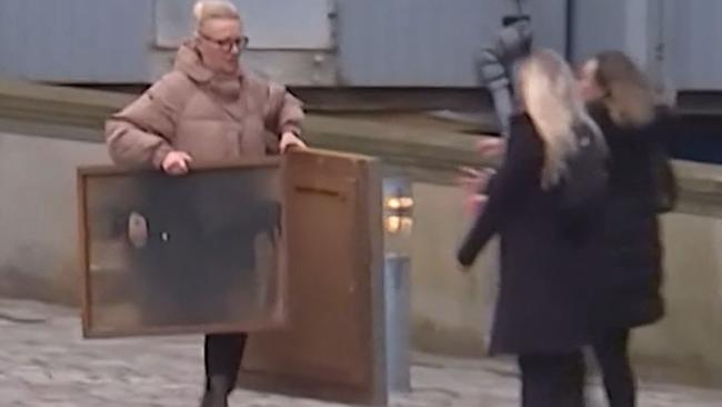 A passer-by runs with paintings from the burning Stock Exchange building in Copenhagen. Picture: BBC.