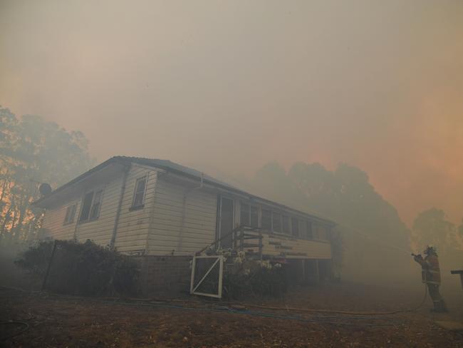 A firefighter hoses down a property in the hope of saving it from nearby bushfires around the town of Nowra in the Australian state of New South Wales on December 31, 2019. - Thousands of holidaymakers and locals were forced to flee to beaches in fire-ravaged southeast Australia on December 31, as blazes ripped through popular tourist areas leaving no escape by land. Picture: Saeed Khan/AFP