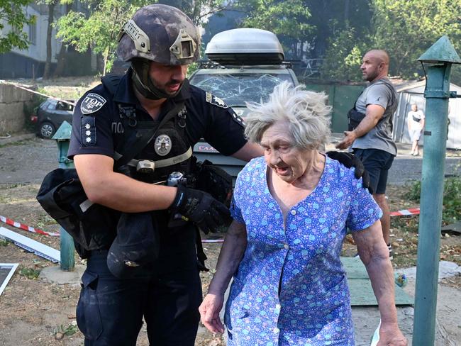 TOPSHOT - A Ukrainian police officer helps an elderly woman to leave the site of a missile attack in Kharkiv on September 15, 2024, amid the Russian invasion of Ukraine. (Photo by SERGEY BOBOK / AFP)