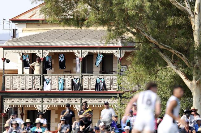 A Port Adelaide supporter stands on his balcony decorated with Port Jumpers as he watches the match between the Crows and Power at Port Pirie. Picture SARAH REED