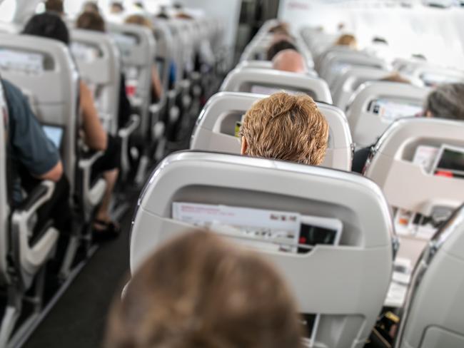 Interior of commercial airplane with passengers in their seats during flight.