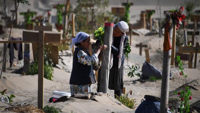 Women decorate a grave in a Uyghur graveyard on the outskirts of Hotan in China's northwest Xinjiang region. Picture: Greg Baker/AFP