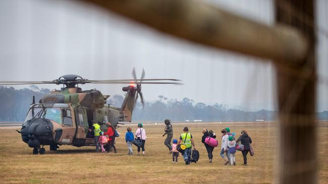 Evacuees board a Royal Australian Navy MRH-90 helicopter at Mallacoota. Picture: AFP