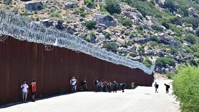 Migrants walk into the US beside the US-Mexico border wall at Jacumba Hot Springs, California. Picture: AFP.