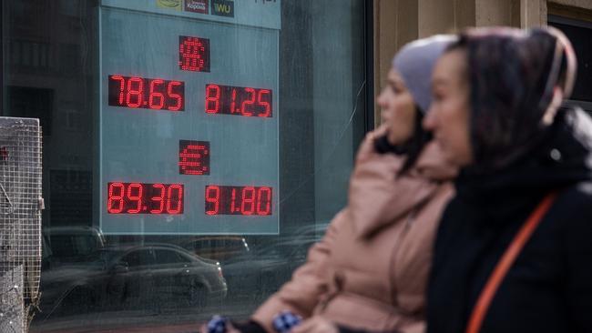 Women walk past a board showing currency exchange rates of the US dollar and the euro against Russian rouble in Moscow. Picture: AFP