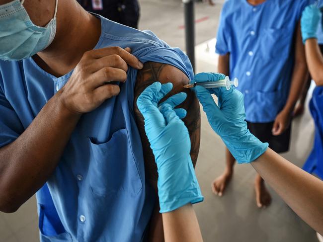 TOPSHOT - Inmates receive doses of the Sinopharm Covid-19 coronavirus vaccine at Chonburi Central Prison on June 25, 2021. (Photo by Lillian SUWANRUMPHA / AFP)