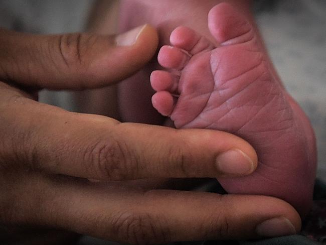 A mother holds the feet of her newborn baby in hospital in Nantes, western France, on July 8, 2018. During a press-conference on January 16, 2024 French President Emmanuel Macron's laid out plans to revive France's sluggish birth rate, promising better parental leave and combat infertility, which he called "the taboo of the century". In 2023, France registered 678,000 births, a drop of 6.6 percent from the previous year, the lowest annual rate since World War II. (Photo by LOIC VENANCE / AFP)