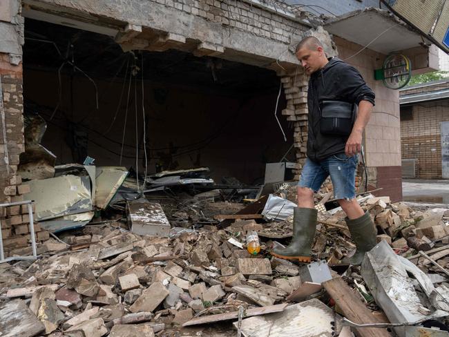 A local resident clears debris of a shop destroyed after a Russian shelling in Kherson, 10km from where an elderly Ukraine priest was struck and killed in a churchyard. Picture: AFP